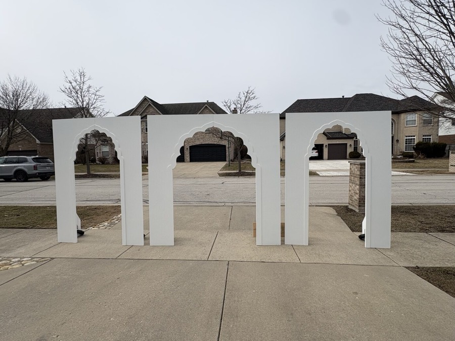 Three white Moroccan-style arches standing in a driveway, built as a wedding backdrop set