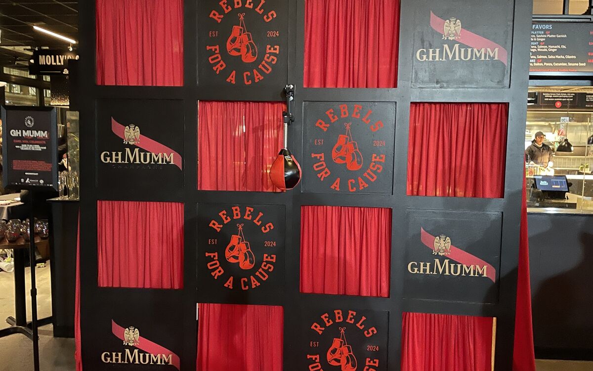 A black-and-red branded photo wall built by MH Build Studio for a G.H. Mumm charity event